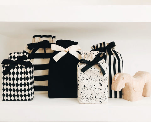 Bag-all Gift Bag Striped Medium collection featuring black and white patterns - striped, solid, diamond, and splatter designs with elegant ribbon bows, displayed on white shelf