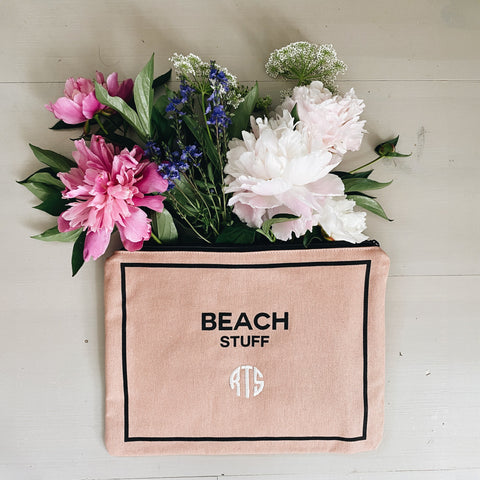 Bag-all pink monogram beach pouch with waterproof lining shown with decorative flowers, featuring "BEACH STUFF" text and personalized initials, perfect for storing beach essentials