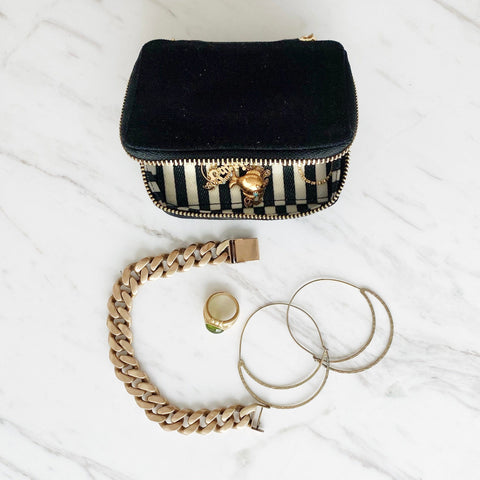 Bag-all Black Jewelry Box with striped lining and gold zipper shown with jewelry pieces on marble surface, perfect for organizing small accessories and trinkets
