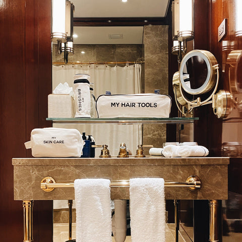 Bag-all Pamper Gift Set Deal 3-Pack Cream featuring luxury cotton organizers for hair tools and skincare displayed on elegant marble vanity with gold accents and magnifying mirror