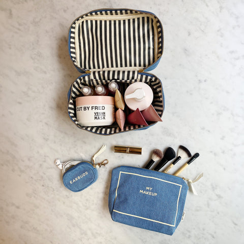 Bag-all Trendy Denim Travel Gift Set featuring makeup box with striped lining, makeup pouch with brushes, and earbuds case in stylish blue denim material, displayed on marble surface
