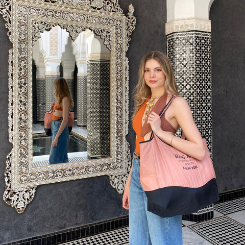 Bag-all Folding Shopping Bag with Zipper Pocket Pouch in pink and black nylon, shown in ornate Moroccan setting with decorative mirror and traditional tile work, demonstrating portable eco-friendly design