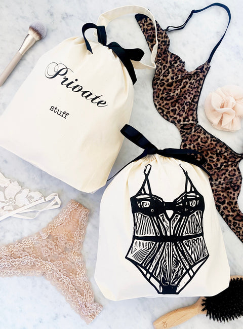 Bag-all Private Stuff Large Bag in cream cotton with black bow, styled with lingerie and beauty accessories. Elegant organizing solution for personal items.