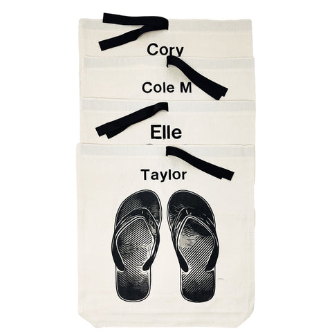Bag-all Flip Flops Shoe Bag in cream canvas with black flip flop graphic and personalized name labels, featuring contrasting black ribbon ties for organized summer storage