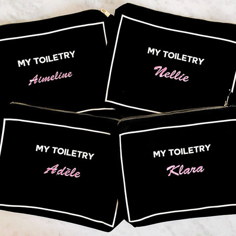 Bag-all Black Toiletry Pouch with Coated Lining featuring personalized names in pink script on black cotton cases with metal zippers and waterproof interior, perfect for travel organizing