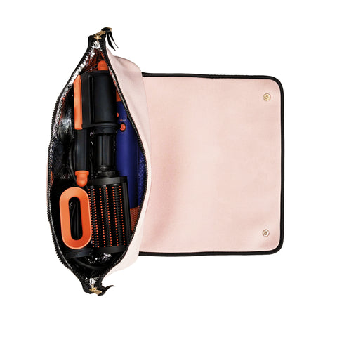 Open pink travel case with heat-resistant mat holding styling tools and hairbrush secured by elastic straps