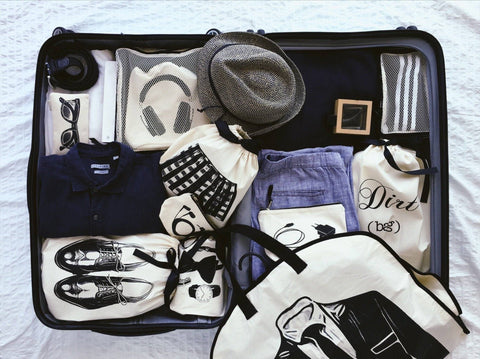 Bag-all Men's Accessories Bag in cream organizes essentials with style - featuring compartments for shoes, headphones, hat, sunglasses, and clothing neatly packed in a sleek travel case