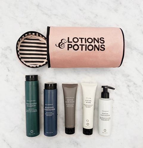 Bag-all Lotions & Potions Travel Case in blush pink with striped waterproof lining, shown with toiletry bottles on marble surface. Cylindrical organizer for travel essentials.