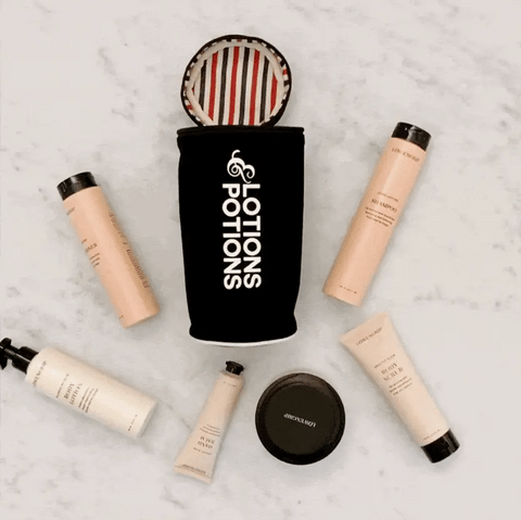 Bag-all Lotions & Potions black travel case displayed with beauty products and toiletries, featuring striped interior lining and white logo text on cotton fabric