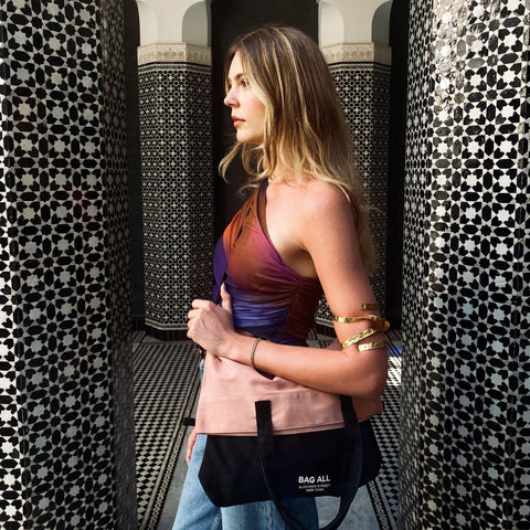 Woman carrying Bag-all 3-Way Tote in Pink/Black, folded as a clutch. Versatile, chic, and perfect for travel