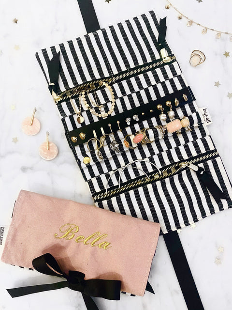 Bag-all Jewelry Organizer Travel Pouch in blush pink with striped interior, featuring multiple compartments, leather earring holder, and ring storage, displayed with jewelry pieces