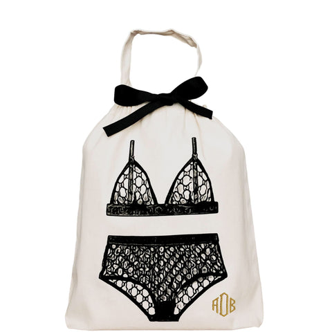 Bag-all London Lingerie Travel Bag in cream cotton with black lace lingerie illustration and decorative bow, featuring monogram detail and drawstring closure