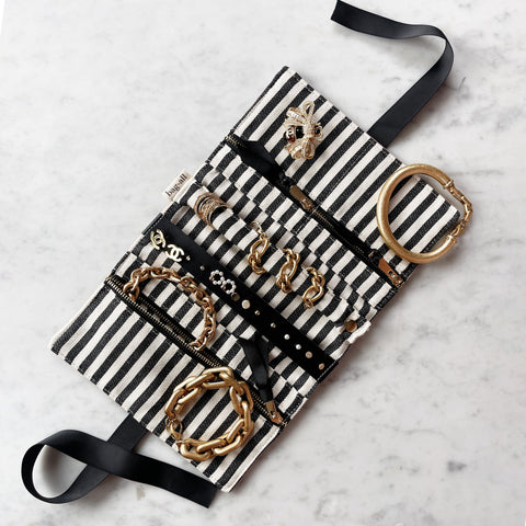 Bag-all Couture Jewelry Roll Medium in cream with black and white stripes, displaying organized gold jewelry, necklaces, and accessories in multiple compartments with ribbon ties