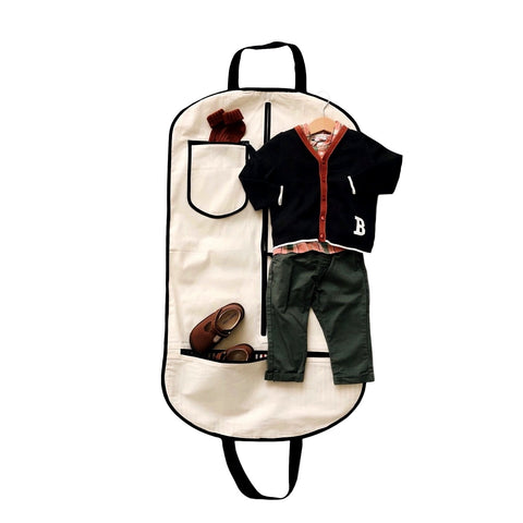 Bag-all Kids Garment Bag Boy in cream canvas with two pockets, showing organized boys outfit with black cardigan, green pants and brown shoes, featuring dual carrying handles