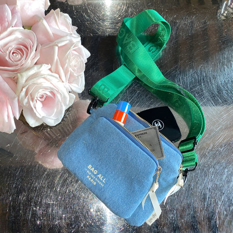 Bag-all Padded Trinket Pouch Double Pocket in Denim with green strap, featuring dual zippered compartments, shown next to pink roses on reflective surface. Versatile organizing pouch for everyday essentials.