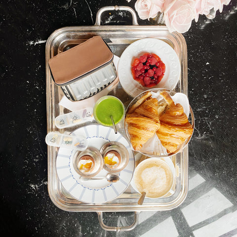 The image shared appears to be unrelated to the pill travel case product. It shows a breakfast or brunch setting with croissants, beverages, and pastries on a silver tray.
For the pill travel case product, here's an appropriate ALT text following your requirements:
Bag-all Large Pill Travel Case in pink blush cotton featuring individual daily pill organizer compartments and secure zipper closure for organized medication storage