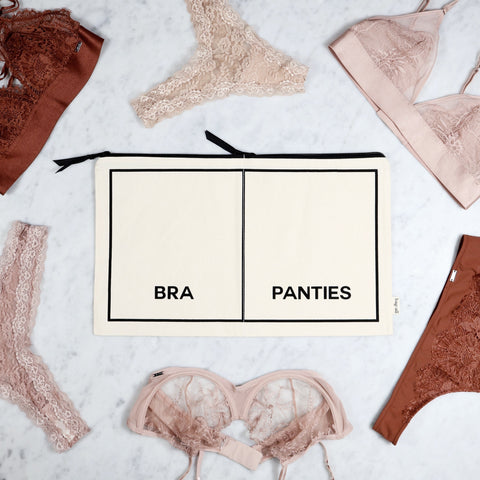 Cream cotton double underwear organizer pouch with bra and panties compartments surrounded by lace lingerie pieces