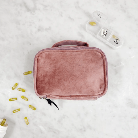 Bag-all Pink Velvet Pill Box with Handle & Weekly Organizer shown with medication capsules and pill container on marble surface, featuring soft plush texture and compact design