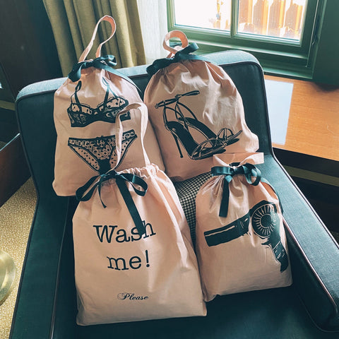 Bag-all Women's Travel Set 4-pack in Pink/Blush featuring organized storage bags for laundry, hair dryer, lingerie, and shoes with elegant black bow details and stylish graphic prints