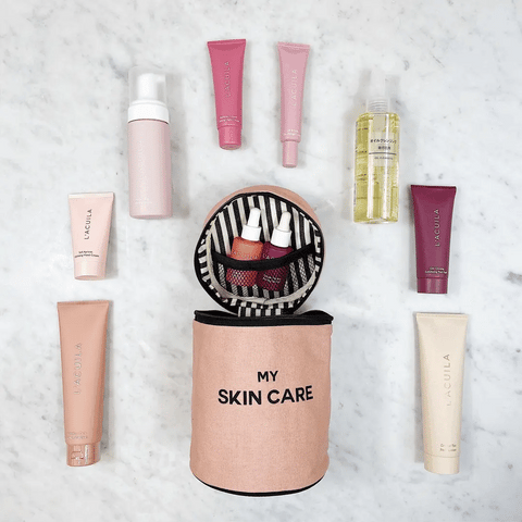 Bag-all Round Skin Care Case with Handle in Pink displaying organized beauty products, featuring striped interior lining and 'My Skin Care' text on blush pink cylindrical container on marble surface