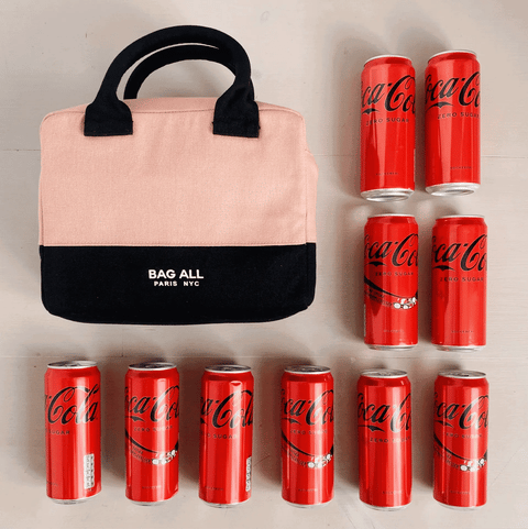 Bag-all Stylish Monogram Lunch Box in pink and black insulated design, shown with Coca-Cola cans for size reference, featuring padded handles and brand logo detail.