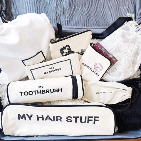 Bag-all Hair Stuff Travel Case in cream with matching organizer bags for toiletries and accessories, featuring black text labels and zipper closures, displayed in suitcase