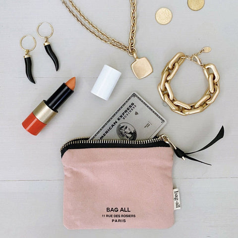 Bag-all Mini Trinket Pouch in pink canvas with black zipper, styled with luxury accessories including gold jewelry, lipstick and credit card against light gray background