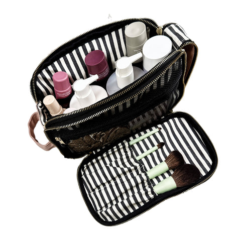 Pink and black triple compartment beauty and toiletry organizer with striped interior and makeup brushes inside
