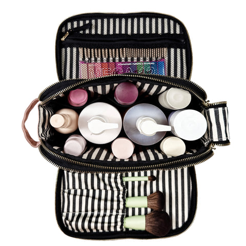 Open pink blush toiletry organizer with striped interior, holding bottles, makeup brushes, and zippered mesh pocket toiletries.
