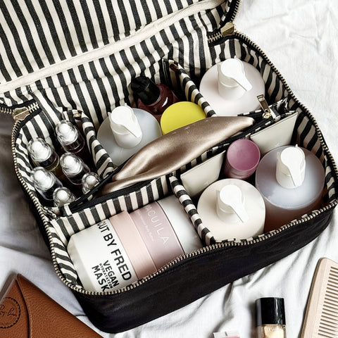 Black large vanity beauty box with striped insert organizer holding various skincare and makeup bottles and containers