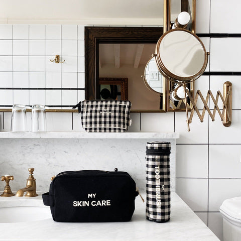Bag-all Toothbrush Travel Case in stylish black and white gingham pattern, displayed on marble counter with matching bathroom accessories and expandable vanity mirror