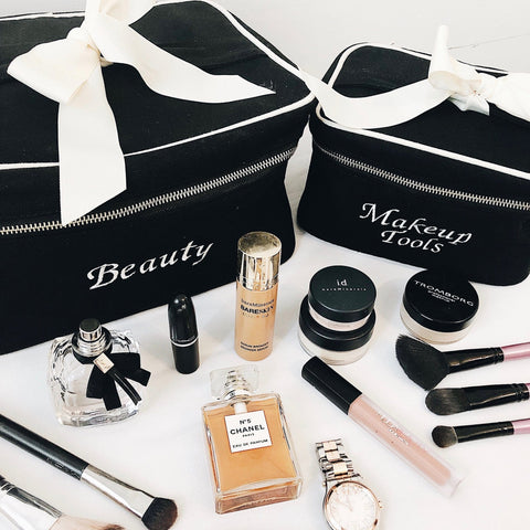 Bag-all Beauty and Makeup Tools organizing cases in black with white bows, displayed with luxury cosmetics, perfumes, and brushes - perfect for personalized monogramming and beauty storage