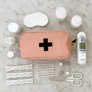 Bag-all First Aid Organizing Pouch in blush pink with medical supplies including bandages, scissors, thermometer, and medicine containers arranged on gray surface