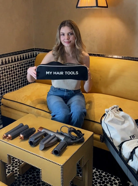 Bag-all Roomy Hair Wrap Tools Travel Case displayed with Dyson Airwrap accessories on decorative gold table, showcasing spacious black case with white text reading "MY HAIR TOOLS" and heat-resistant interior lining