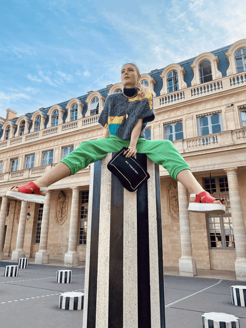 Bag-all Black Toiletry Pouch with coated lining shown in front of Parisian architecture, perched on a striped Buren column at Palais Royal, featuring sleek modern design with classic backdrop