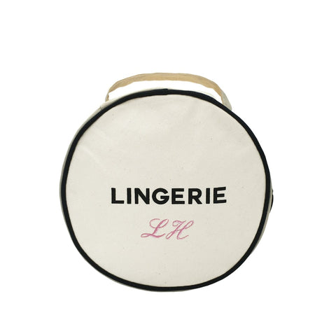 Bag-all Round Lingerie Case in cream canvas with black trim, featuring 'LINGERIE' text and monogram option, perfect for organized travel storage