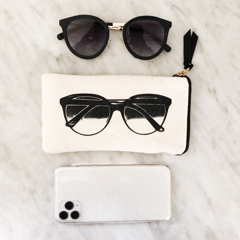 Bag-all Glasses Case with Outside Pocket in Cream featuring black sunglasses print, zipper closure and functional exterior pocket on marble surface with matching sunglasses