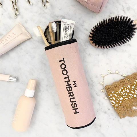 Bag-all pink Toothbrush Travel Case holds multiple toothbrushes and toothpaste, displayed on marble surface with hairbrush and beauty accessories, perfect for bathroom organization