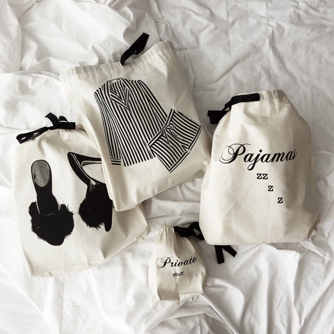 Bag-all cream cotton drawstring travel bags featuring Pajamas Zzzz design, with coordinating bags for slippers and private items, arranged on white fabric