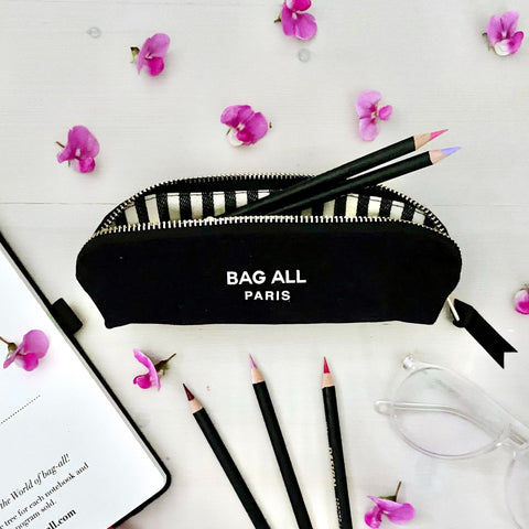 Bag-all Black Pencil Case with striped zipper detail styled with pencils and pink flowers on white surface, perfect for organizing stationery in Parisian style