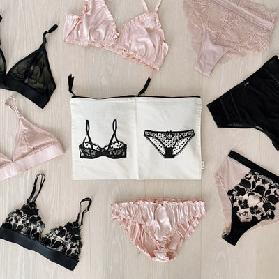 Bag-all Double Lingerie Packing Pouch in Cream with illustrated bra and panty design, surrounded by pink and black lingerie sets on light wooden surface