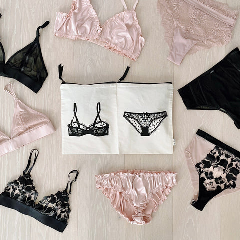 Bag-all Travel Glam 4-Pack featuring cream cotton organizer with lingerie illustration, surrounded by pink and black lace bralettes and matching underwear sets, perfect for stylish travel storage