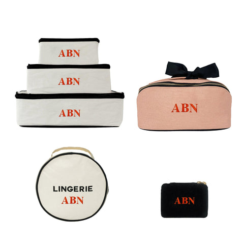 Bag-all Organized Traveler Essentials 4-set featuring monogrammed packing cubes in white and pink, lingerie case, and jewelry pouch with ABN personalization and black trim details