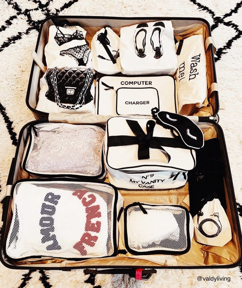 Bag-all Quilted Handbag Travel Bag in cream shown with organized travel compartments featuring labeled storage pouches for accessories, electronics, and vanity items, neatly arranged in a suitcase